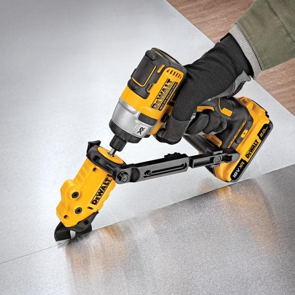 A person wearing gloves uses a DEWALT DT70620 power tool with an attachment to cut through a sheet of metal.
